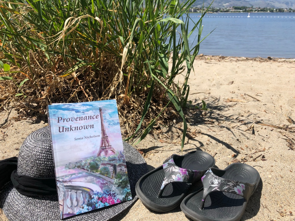 Hat, book, and sandals on beach.
