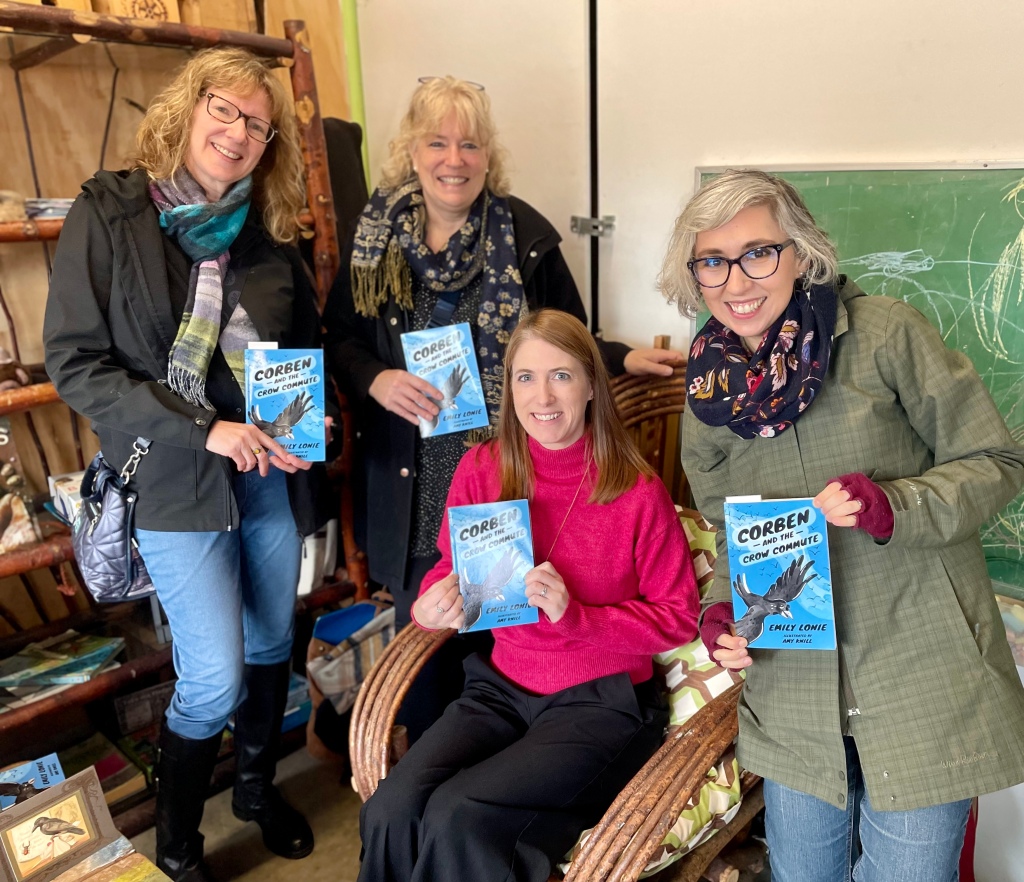 Group of four women each holding a copy of Corben and the Crow Commute by Emily Lonie.